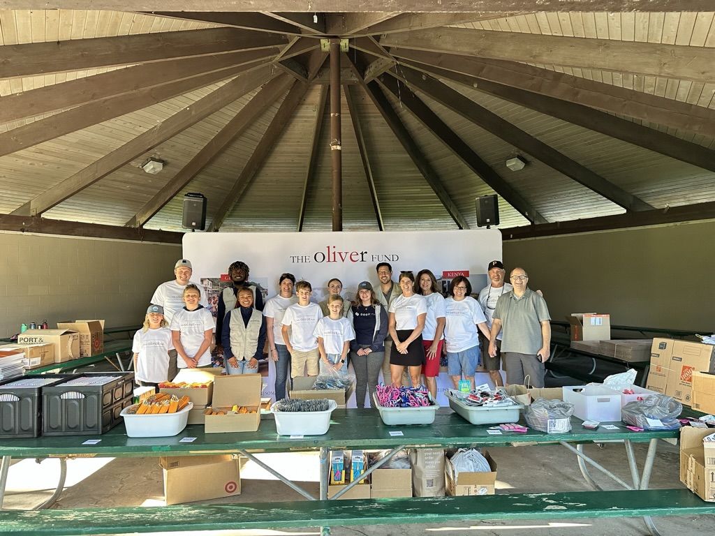 Ollie's Army volunteers in Oliver Fund shirts stand behind tables of school supplies