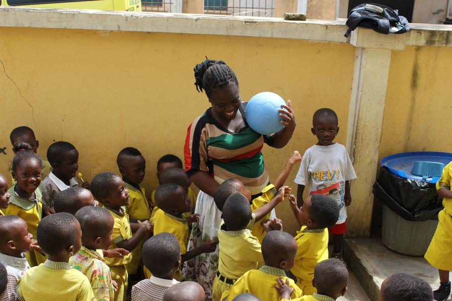 Young students in yellow uniforms reach for a new ball
